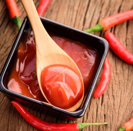 Red hot chilli sauce in wood spoonの写真素材