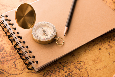 Compass with note book and pencil on old map vintage style