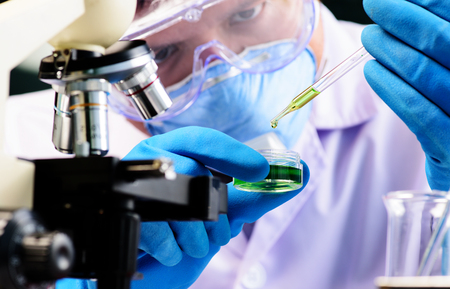 Conical flask in scientist hand with lab glassware background, Laboratory research conceptの写真素材