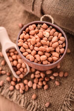 close up of raw peanuts or arachis in wood cup on sack backgroundの写真素材