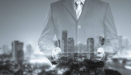 Double exposure of success businessman using digital tablet with city landscape backgroundの写真素材