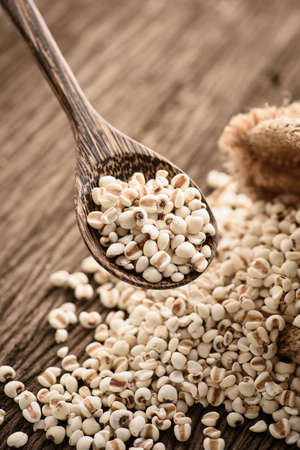 close up of organic millet in wood spoon on wooden rustic table