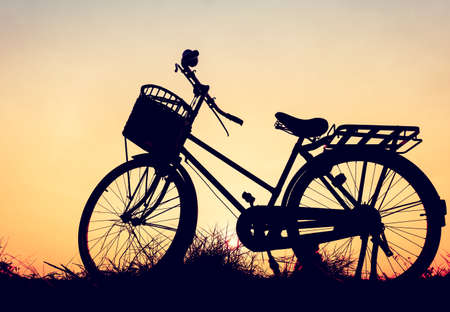 beautiful landscape image with Bicycle silhouette  at sunsetの写真素材