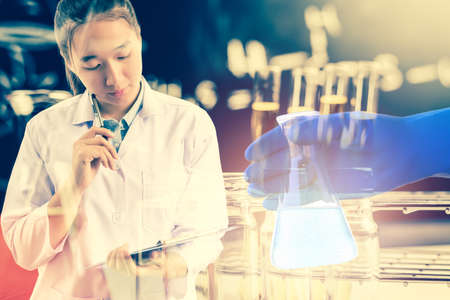 Double exposure of Scientists or doctor is thinking for writing report with Laboratory glassware containing chemical liquid, science research concept,vintage process styleの写真素材
