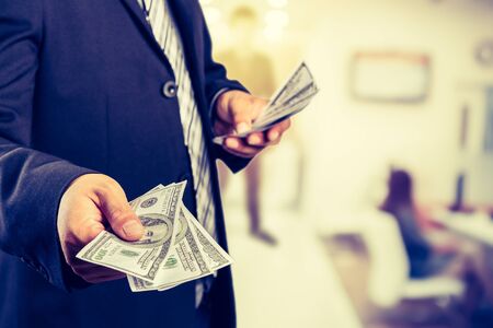 Businessman with money in hand, US dollar (USD) bills - investment, success and profitable business conceptsの写真素材