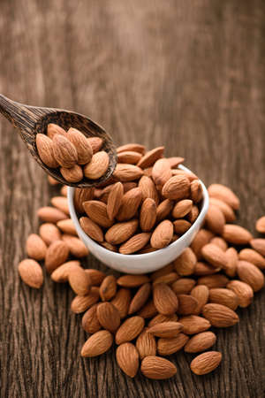 close up of almonds in a wood spoon on grained wood backgroundの写真素材