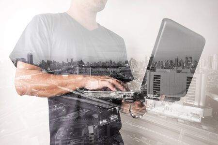 Double exposure of success businessman using labtop with with city landscape backgroundの写真素材