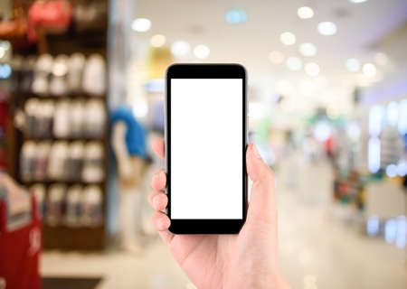 hand holding Smart phone with white screen in hand on blurred in shopping mall backgroundの写真素材