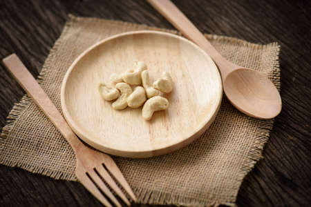 close up of cashew nut in wood dish with spoon and forkの写真素材