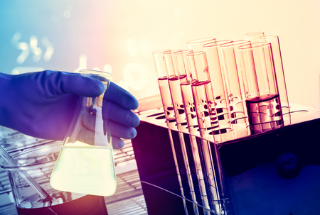 Flask in scientist hand with test tube in rackの写真素材