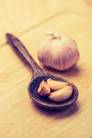 garlic in wooden spoon on a tableの写真素材