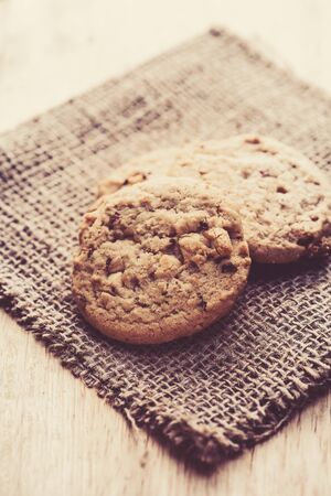 Chocolate cookies on white linen napkin on wooden table. Chocolate chip cookies shot on sackの写真素材
