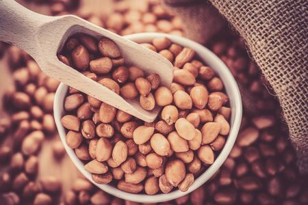 close up of raw peanuts or arachis in wood scoop on sack backgroundの写真素材