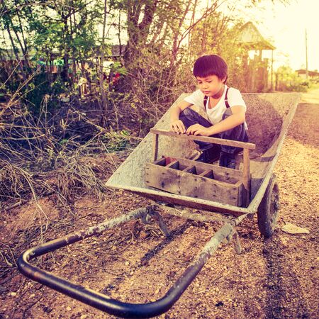 Cute Asian boy sit on a cartの写真素材