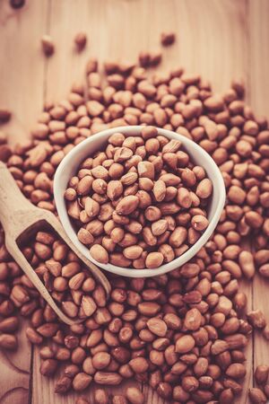 close up of raw peanuts or arachis in ceramic bowl on wood backgroundの写真素材