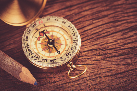 Old  gold vintage compass with pencil on wood backgroundの写真素材