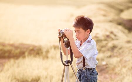 asian boy with classic camera is shooting in the farm