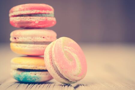 A lot of french colorful macarons on a woody floor in vintage tone styleの写真素材