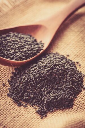 black Sesame close up shot in wood spoon on sack backgroundの写真素材