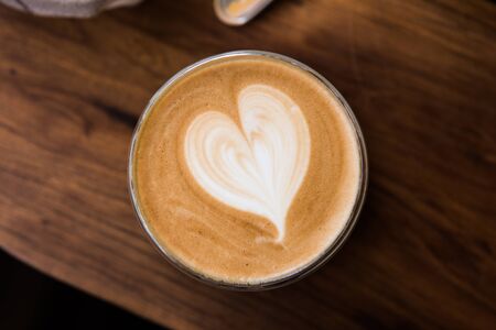 A Cup of hot latte art coffee on wooden tableの写真素材