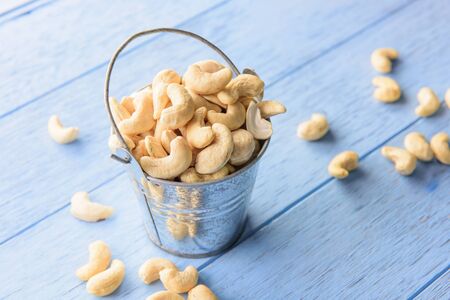 raw cashew nuts in bucket on blue wood tableの写真素材