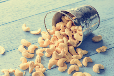 raw cashew nuts in bucket on blue wood tableの写真素材