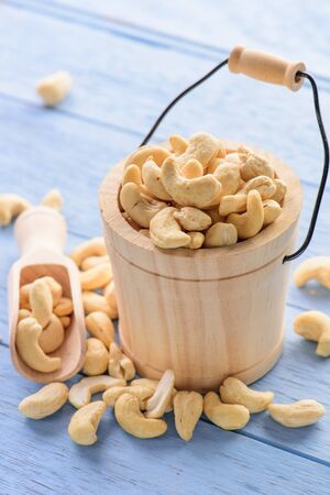 raw cashew nuts in wood bucket on blue wood tableの写真素材