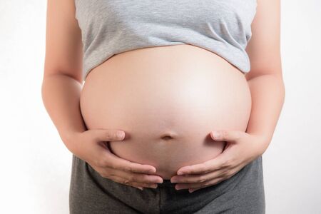 pregnant woman touching her belly on white backgroundの写真素材