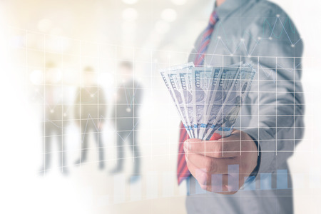 Businessman with money in hand, US dollar (USD) bills - investment, success and profitable business concepts.Forex graph on background. A metaphor of international financial consultingの写真素材