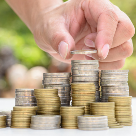 Close up of male hand stacking gold coins with green bokeh background ,Business Finance and Money...