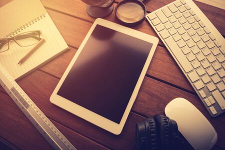 mockup tablet on wood desk. black display.keyboard and office stuff, workplace, top viewの写真素材