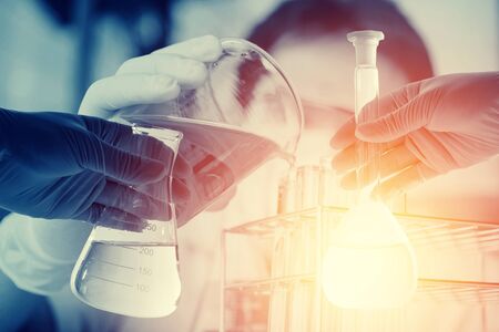 Conical flask in scientist hand with lab glassware background, Laboratory research concept