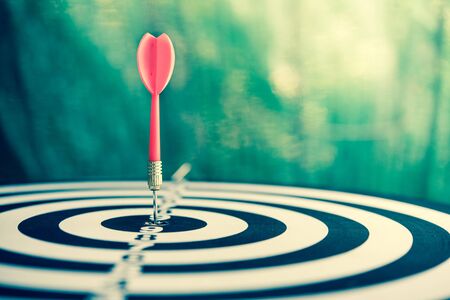Red dart arrow hitting in the target center of dartboardの写真素材