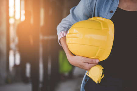engineer holding yellow helmet for workers security on Construction site.の写真素材