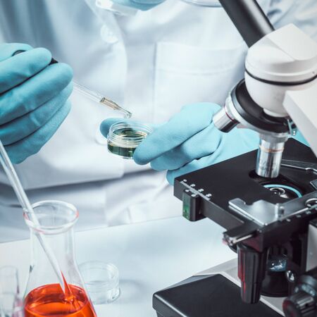 Conical flask in scientist hand with microscope and lab glassware background, Laboratory research...