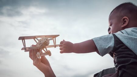 The child is playing an airplane model with his mother.の写真素材