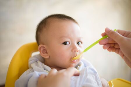 baby child sitting in chair with a spoon