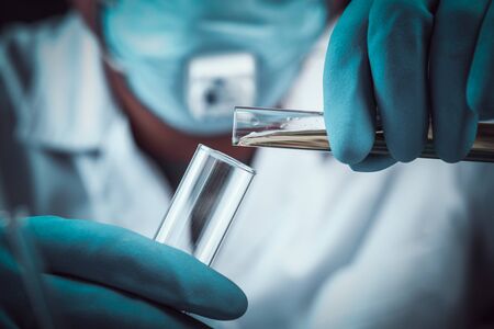 scientist dropping chemical liquid to flask with lab glassware background, Laboratory research concept,Researcher is dropping the reagent into test tube.の写真素材