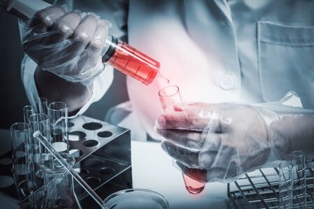 scientist dropping chemical liquid to flask with lab glassware background, Laboratory research...