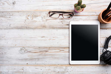 White Tablet With Blank Screen On Wooden Desk With Stationery Objects , Top View  with copy space.の写真素材