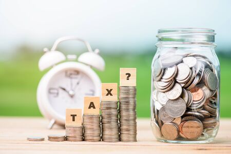 Tax Concept with wooden block on stacked coinsの写真素材