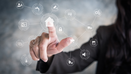 Circular futuristic interface of smart home automation assistant on a virtual screen and a user touching a home buttonの写真素材