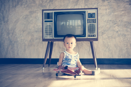 Asian cute baby boy playing with a plane model.vintage tone styleの写真素材