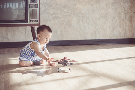 Asian cute baby boy playing with a plane model.vintage tone styleの写真素材