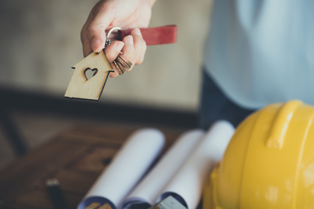 hand hold key and house model in saving plan for residence of people in society, purchasing home for living of dream of community lives.の写真素材