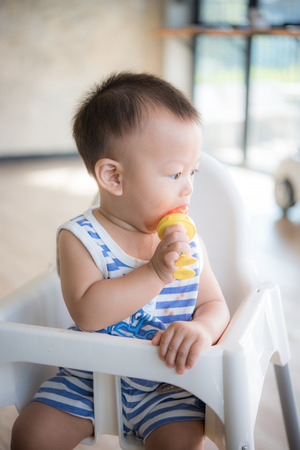 Asian cute baby boy are eating fruit from the accessory.