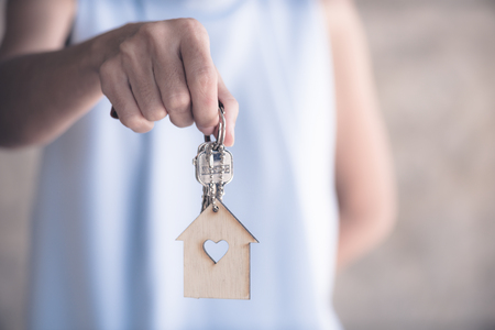 hand hold key and house model in saving plan for residence of people in society, purchasing home for living of dream of community lives.の写真素材