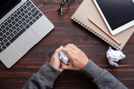 Man hand is crumpled paper at men table in the office trying to come up with the right solution