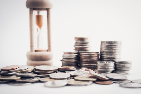 sandglass and rows of coins for time of finance and business conceptの写真素材