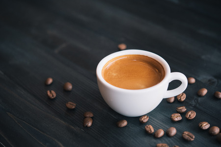 Fresh tasty espresso cup of hot coffee with coffee beans on dark backgroundの写真素材